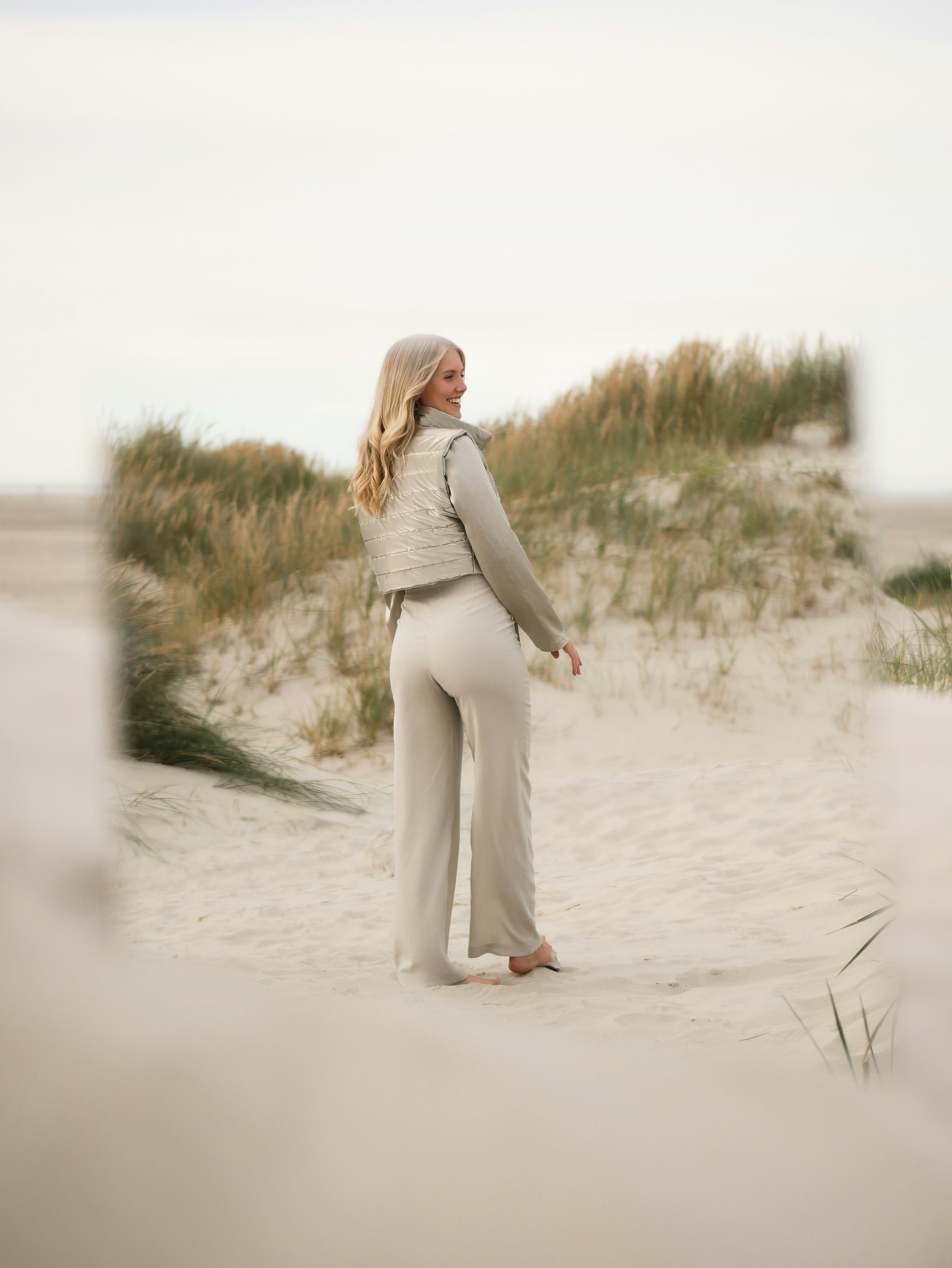 woman in gray long sleeve dress walking on white sand during daytime